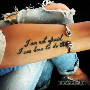 Фото тату надписи 'I am not afraid I was born to do this' на запястье девушки. Черно-белый рисунок татуировки выполнен каллиграфическим шрифтом.
