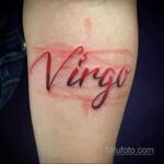 Фото тату надписи 'Virgo' на руке: красная надпись, выполненная каллиграфическим шрифтом, символизирующая знак зодиака Дева.
