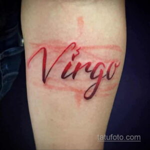 Фото тату надписи 'Virgo' на руке: красная надпись, выполненная каллиграфическим шрифтом, символизирующая знак зодиака Дева.