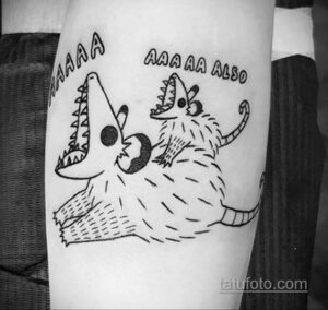 Черно-белое фото тату енота, кричащего 'AAAAA AAA AA ALSO' на руке. Мультяшный стиль с острыми зубами и выразительной мимикой.
