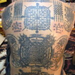 Фото тату: детализированная сакральная татуировка, покрывающая всю спину мужчины, с изображением символов, драконов и геометрических узоров.