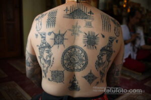 Фото тату: масштабная татуировка с множеством сакральных символов и изображений мифических существ, покрывающая всю спину мужчины. Детализированный рисунок татуировки в стиле сак янт.