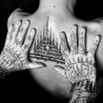 Фотография мужчины с сак янт татуировками на груди и руках, демонстрирующими сложные узоры и символы.