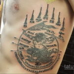 Фото тату: черная сакральная татуировка на боку и спине мужчины, изображающая мифическое существо.