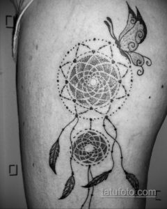 Фото тату ловца снов, выполненного в технике dotwork. Рядом с ловцом снов изображена бабочка. Черно-белая татуировка на руке.
