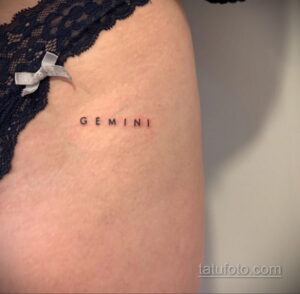Фото тату надписи 'Gemini' выполненной тонким шрифтом на коже руки. Небольшая и изящная татуировка, символизирующая знак зодиака Близнецы.
