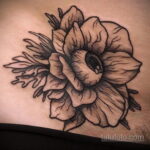 Фото тату цветка с глазом в центре, выполненного в технике blackwork на плече. Детализированный рисунок татуировки с реалистичным изображением глаза.