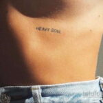 Фото тату с надписью 'Heavy Soul' на боку, выполненное тонким шрифтом в минималистичном стиле. Простой и лаконичный рисунок татуировки.