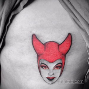 Фото тату лица злой королевы из мультфильма на плече. Цветной рисунок татуировки с ярким макияжем и выразительным взглядом.