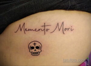 Фото тату: татуировка с надписью 'Memento Mori' и изображением черепа с крестом, выполненная в минималистичном стиле. Символичный рисунок татуировки.