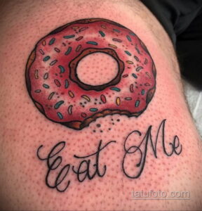 Фото тату: рисунок розового пончика с посыпкой и надписью "Eat Me" на коже. Провокационный и забавный дизайн.