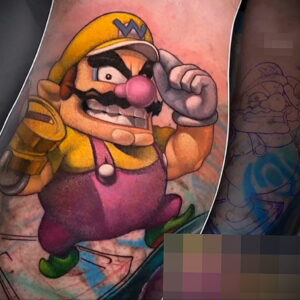 Фото тату: Waluigi из Super Mario Bros., в динамичной позе, яркие цвета, на руке. Идеи для тату для поклонников Nintendo.