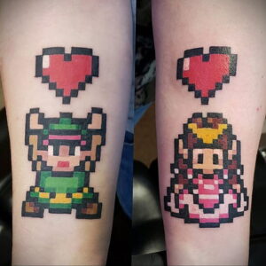 Фото тату: Link и Zelda в пиксельном стиле, красное сердце между ними, на руках. Идеи для парных татуировок для фанатов The Legend of Zelda.
