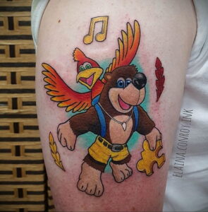 Фото тату: Banjo и Kazooie из игры Banjo-Kazooie, музыкальные ноты, яркие цвета, на руке. Идеи для тату, вдохновленные видеоиграми.