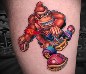 Фото тату: Donkey Kong, катающийся на скейтборде, яркие цвета, детальная проработка, на предплечье. Идеи для тату фанатам видеоигр.