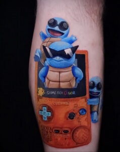 Фото тату на руке: яркая татуировка с изображением покемона Squirtle на фоне игровой консоли Game Boy Color.