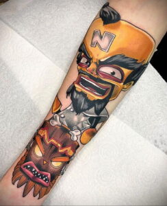 Фото тату на руке: яркая татуировка с изображением персонажа Crash Bandicoot и маски вуду в стиле ретро.