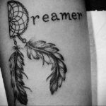 Фотография татуировки ловца снов с надписью 'Dreamer' на руке, выполненной в черно-белом стиле.