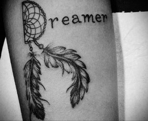 Фотография татуировки ловца снов с надписью 'Dreamer' на руке, выполненной в черно-белом стиле.