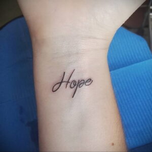 Фото тату: небольшая татуировка надписи 'Hope' на запястье. Простой и вдохновляющий рисунок татуировки.