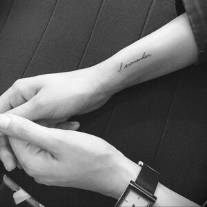 Фото тату: Надпись 'I surrender' на предплечье. Черно-белый рисунок татуировки, выполненный тонким шрифтом, символизирует смирение и принятие.