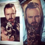 Фото тату на руке с реалистичным портретом Джесси Пинкмана из сериала Breaking Bad с пистолетом в руке. Детализированный рисунок татуировки.