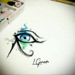Фото тату: реалистичный рисунок глаза Гора с акварельными разводами, выполненный в сине-зеленых тонах. Эскиз татуировки символизирует защиту и здоровье.