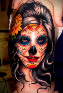Фото тату: красочная татуировка в стиле сахарной черепушки (calavera) на плече. Детализированный рисунок с цветами и яркими узорами.