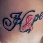 Фото тату надписи "Hope" выполненной красивым шрифтом с розовой лентой, символизирующей надежду и борьбу с раком.
