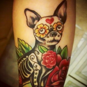 Фото тату чихуахуа в стиле Day of the Dead, украшенного цветами и узорами. Красочный и оригинальный рисунок татуировки.