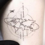 Простая и элегантная татуировка с изображением карты мира и летящего самолета, расположенная на боку.