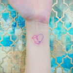 Фото минималистичной татуировки на запястье, изображающей два переплетенных сердца, выполненных тонкими линиями в розовом и фиолетовом цветах.