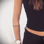 Фото тату в виде тонких черных линий, образующих браслет на предплечье. Минималистичный и стильный рисунок.