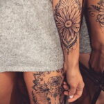 Фото декоративной татуировки в стиле Mandala на бедрах. Сложный узор с цветочными элементами и геометрическими фигурами.