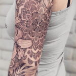 Фото татуировки в стиле геометрия: рукав, покрытый сложным узором из мандалы, цветов и растительных элементов, выполненный в черном цвете.