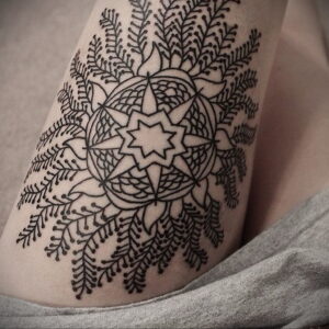 Фото тату на бедре: сложная мандала, выполненная в технике blackwork. Геометрический рисунок татуировки с глубоким символическим значением.