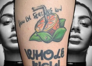 Фото тату апельсина, разрезанного пополам, с надписью 'How I'm Feeling Now' и 'WHOLE BITCH' на руке.