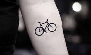 Фото тату простого контурного рисунка велосипеда на руке. Минималистичный эскиз татуировки в черном цвете, идеально подходит для первого тату.