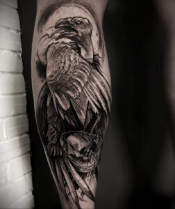 Фото тату на предплечье: реалистичный ворон, череп, черно-серые тона, детализированный рисунок, эскиз татуировки.