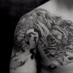 Фото татуировки японского дракона на плече. Детализированный рисунок с использованием черного и серого цветов.