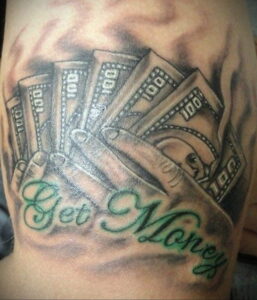 Фото тату: рука, держащая пачку долларов, с надписью 'Get Money'. Яркая татуировка с использованием зеленых и серых оттенков.