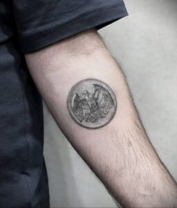 Черно-серая татуировка на предплечье с изображением орла в круге, выполненная в реалистичном стиле. Идеальный эскиз тату для любителей символизма.