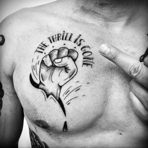Фото тату на груди мужчины: сжатый кулак с надписью 'THE THRILL IS GONE' и падающая капля слезы.
