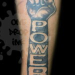 Фото тату на предплечье: кулак с надписью 'POWER'. Черно-серая татуировка.