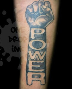 Фото тату на предплечье: кулак с надписью 'POWER'. Черно-серая татуировка.