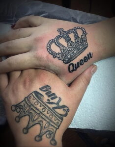 Фото парных татуировок на руках, изображающих короны и надписи 'King' и 'Queen', выполненных в черном цвете.