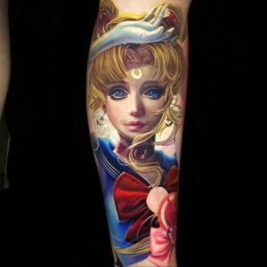 Фотография яркой татуировки на руке, изображающей Sailor Moon. Рисунок выполнен в стиле аниме с использованием ярких цветов и детализированной прорисовкой.