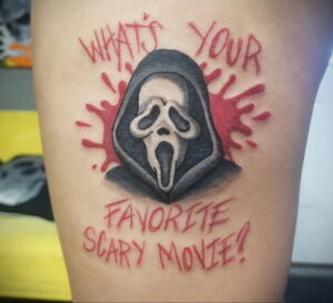 Татуировка Ghostface с надписью "What's your favorite scary movie?". Маска злодея окружена красными брызгами, имитирующими кровь.