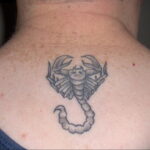 Фото тату скорпиона в стиле blackwork, расположенного на спине мужчины. Четкие линии и минималистичный дизайн.