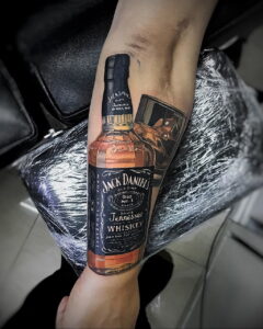 Фото тату на ноге с изображением бутылки виски Jack Daniel's и классического автомобиля. Реалистичный стиль, яркие цвета.